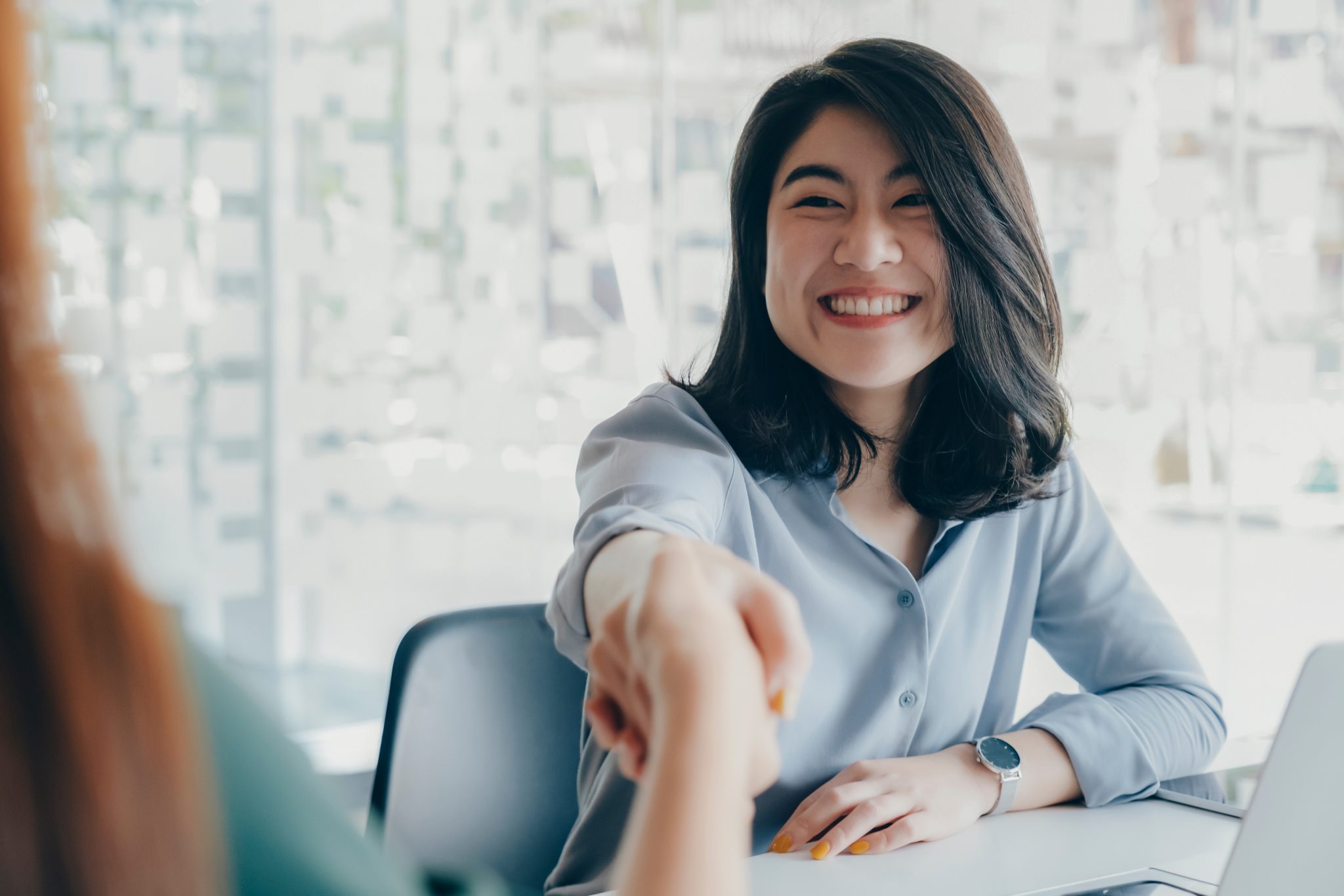 Two women shaking hands over a desk