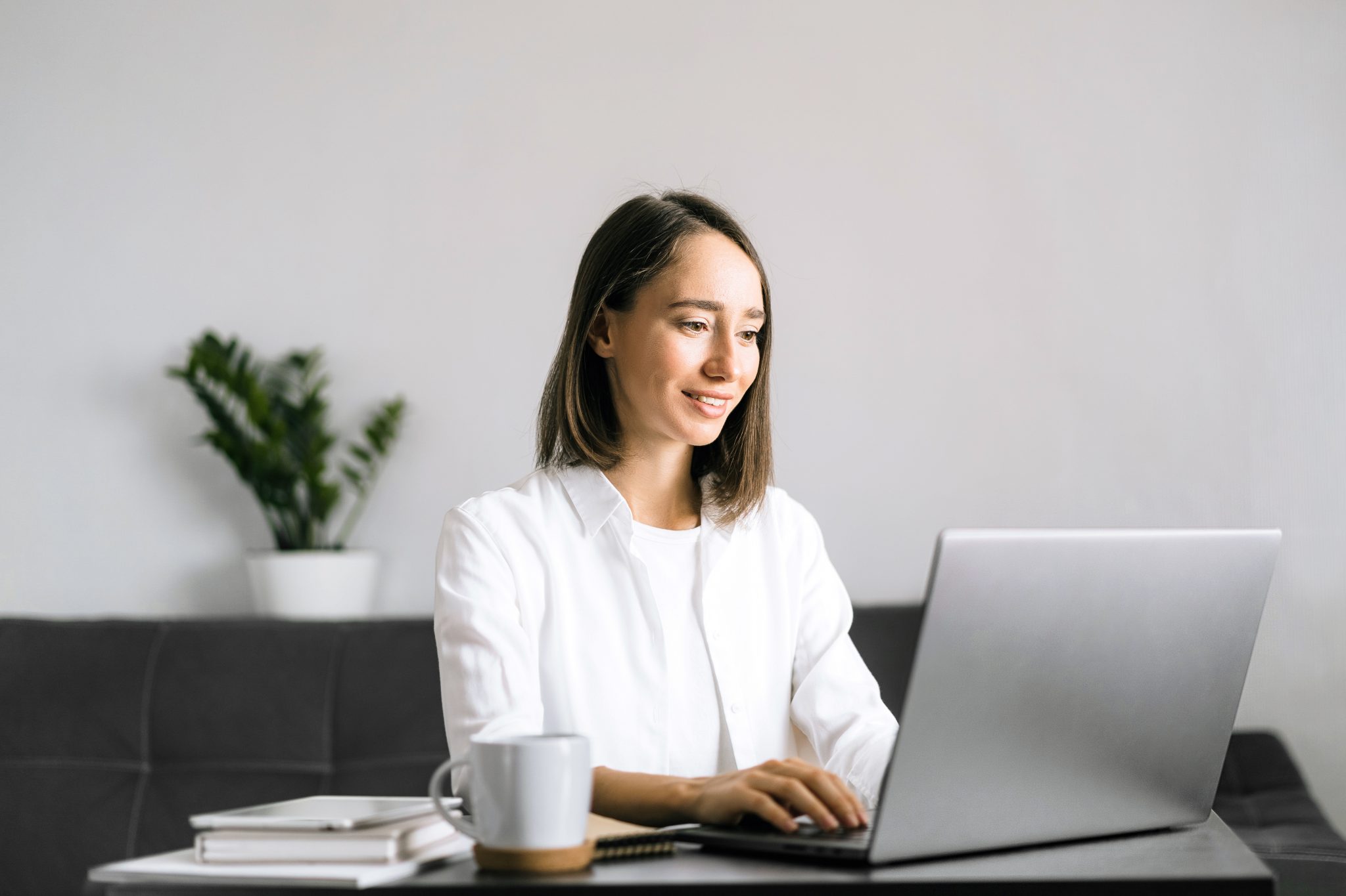 Young woman sitting at the table and using laptop.