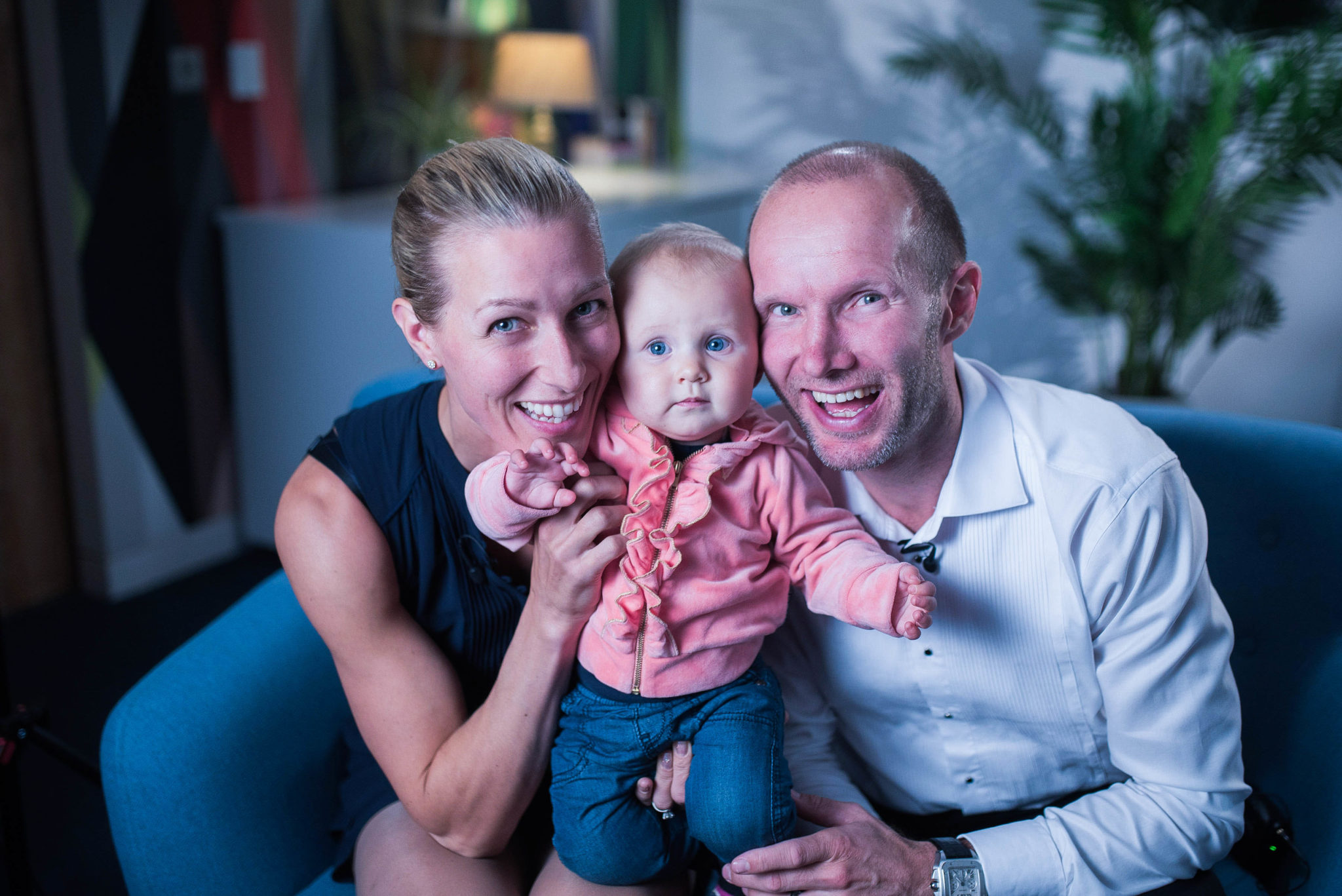 A smiling couple seated with their baby son between them