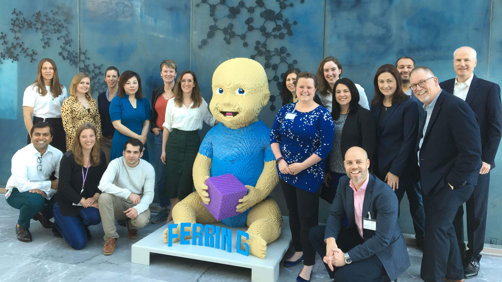 Ferring colleagues pose with a baby statue made of Lego